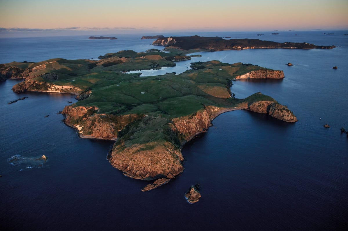 Aerial view of a Mediterranean archipelago at dusk with rocky islands surrounded by turquoise and deep blue waters at sunset