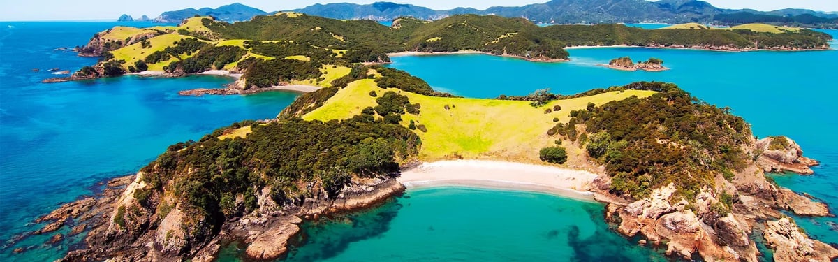Aerial view of a crescent-shaped sandy beach surrounded by forested hills and turquoise ocean waters